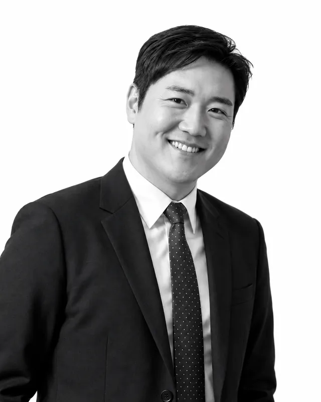 John Min, Principal of JKM Architecture, smiling in a black-and-white portrait